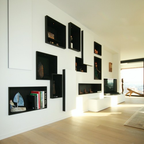 In de woonkamer wouden de eigenaars hun kunstobjecten op een speciale manier uitstallen. Wij stelden deze alternatieve wandkast voor.  Het lijken fotokaders waarin de kunstvoorwerpen helemaal tot hun recht komen. Door te spelen met verschillende afmetingen en vormen zorgden we zelf mee voor extra kunstbeleving in huis. Een wandkast met een artistieke twist dus. Kast-ID Antwerpen